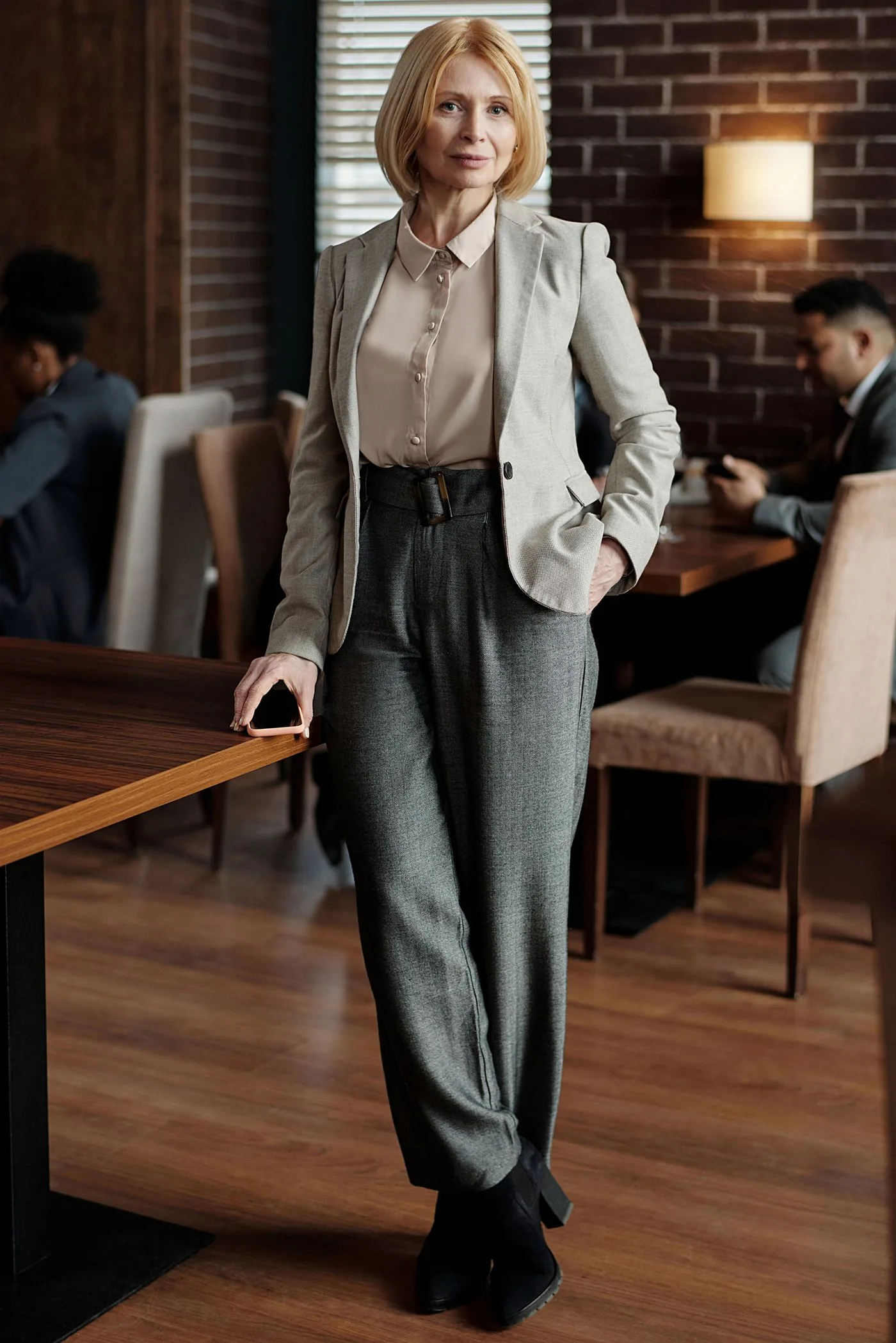 A woman in a beige blazer standing beside a café table
