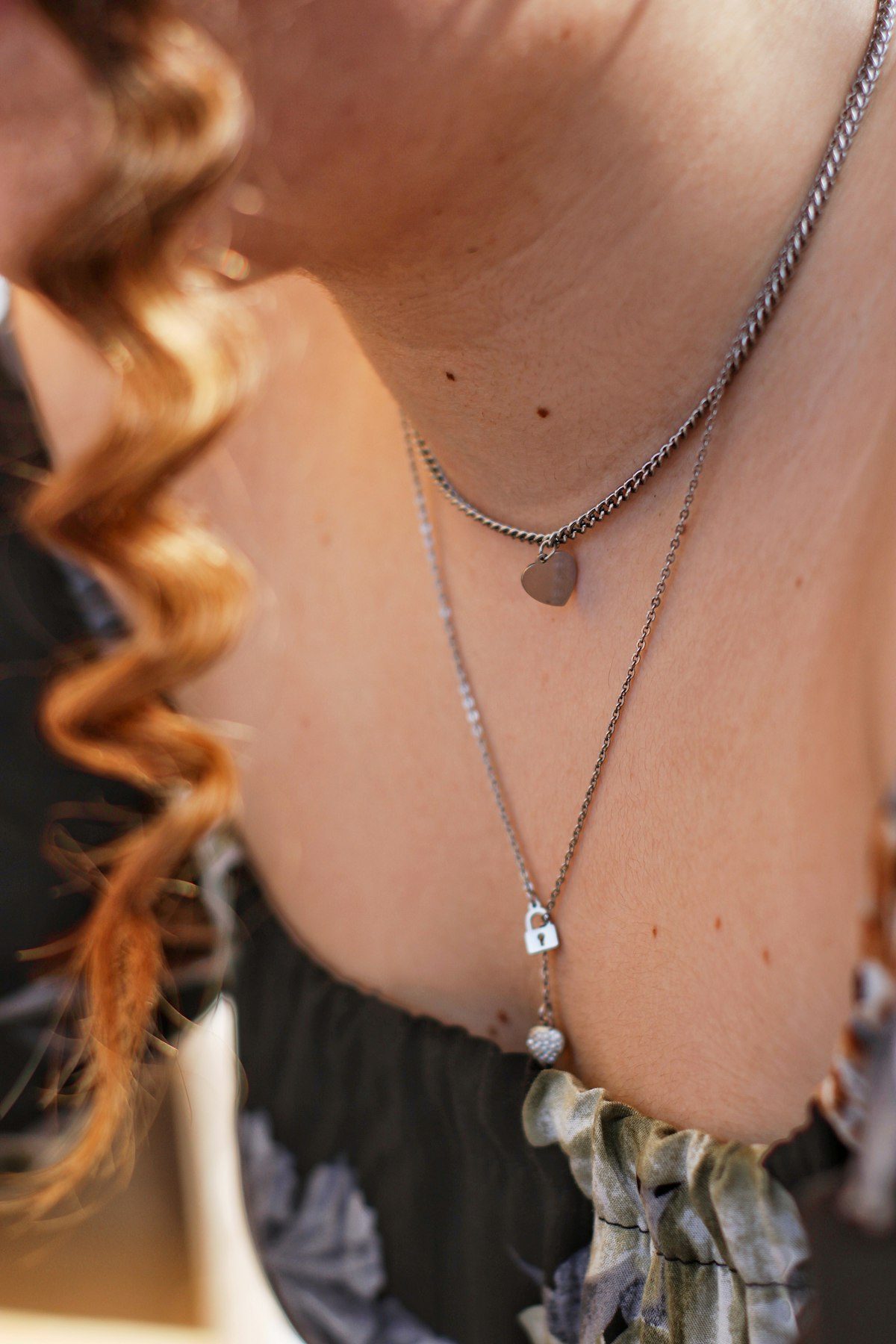 Layered silver-coloured necklaces worn above a dark top