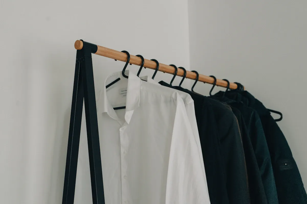 White and dark garments hanging together on a wooden rail