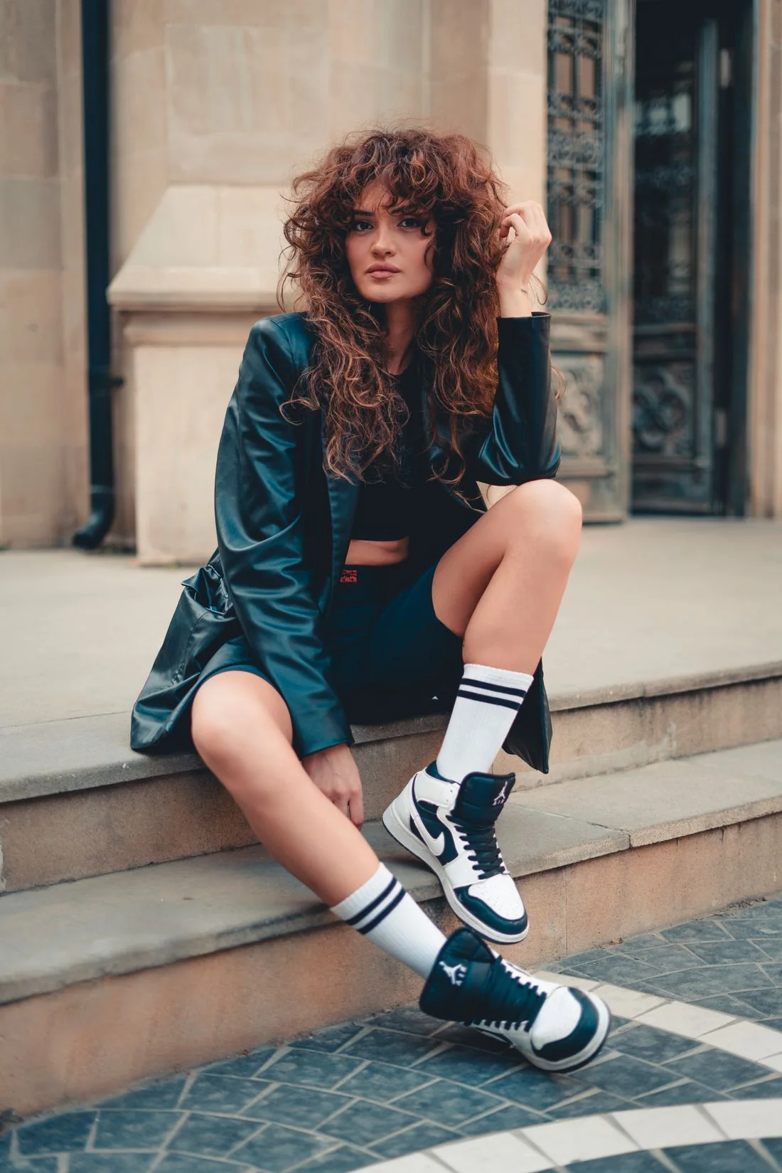 Woman wearing sneakers seated on city steps