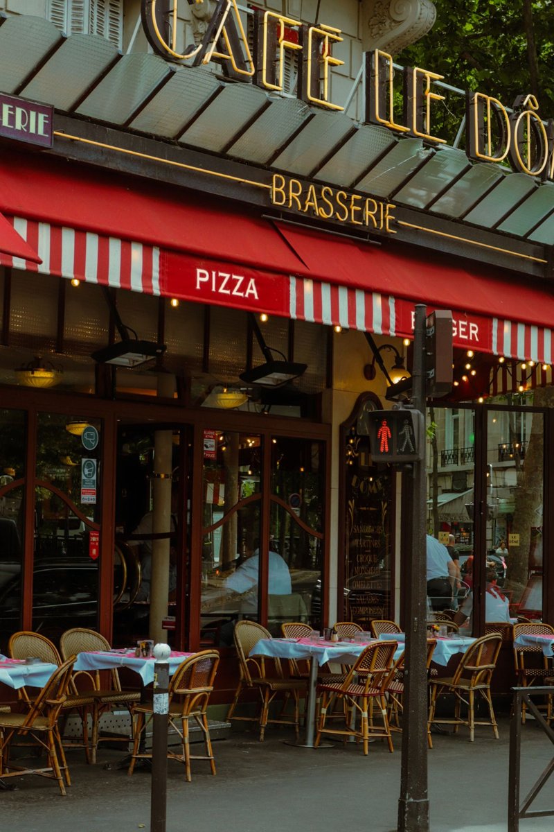 A brasserie entrance with red awnings and outdoor seating