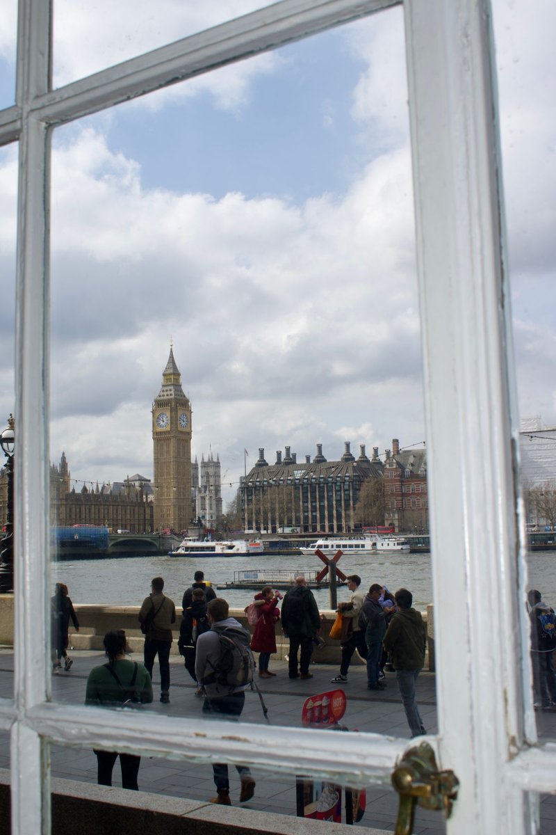 Big Ben and the Thames seen through a pale architectural opening in London