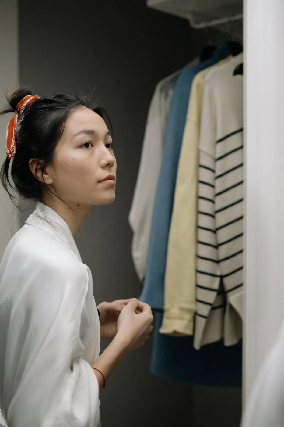 A woman wearing a white jacket beside a slatted wall.