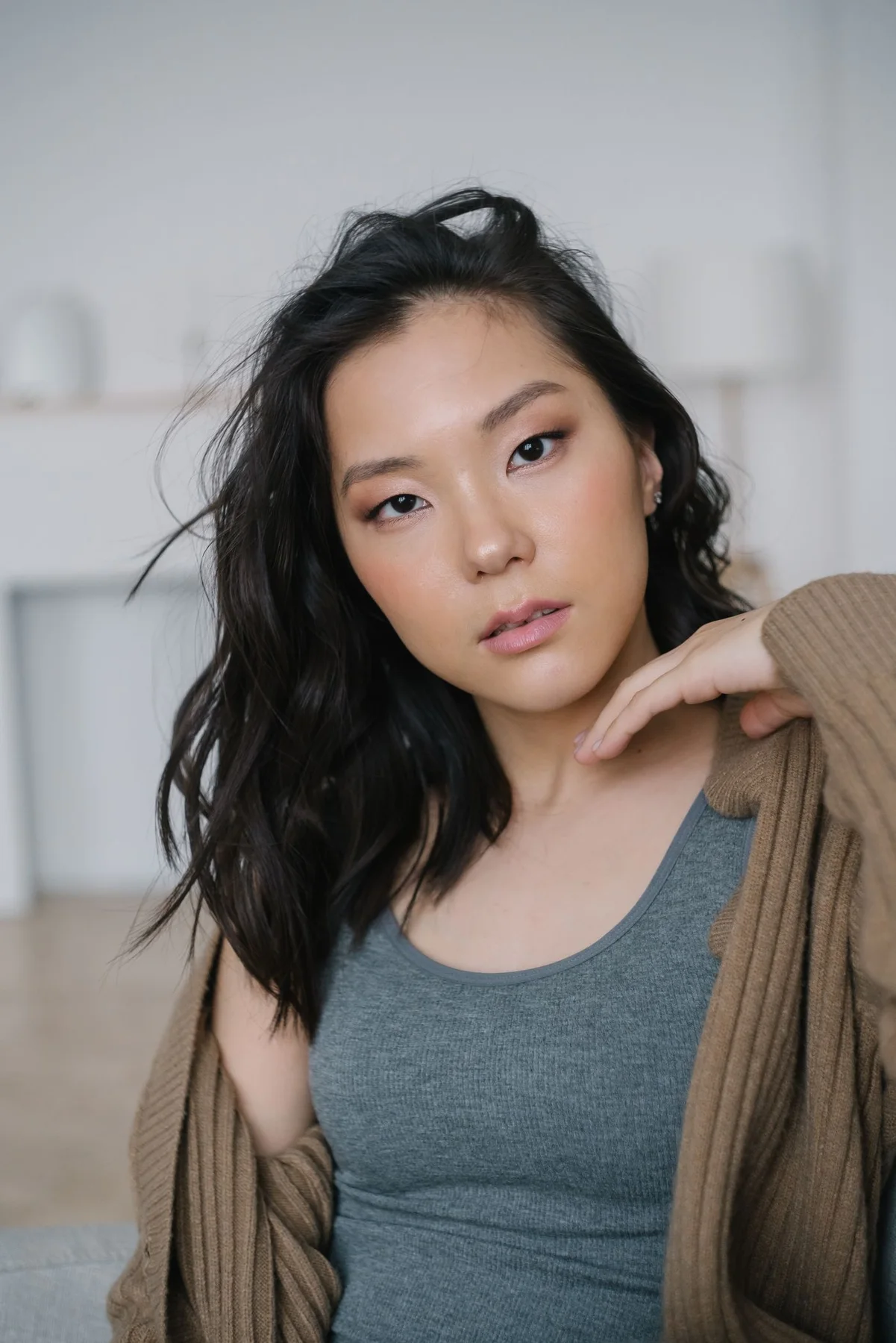 A woman wearing a gray cardigan over a dark top.