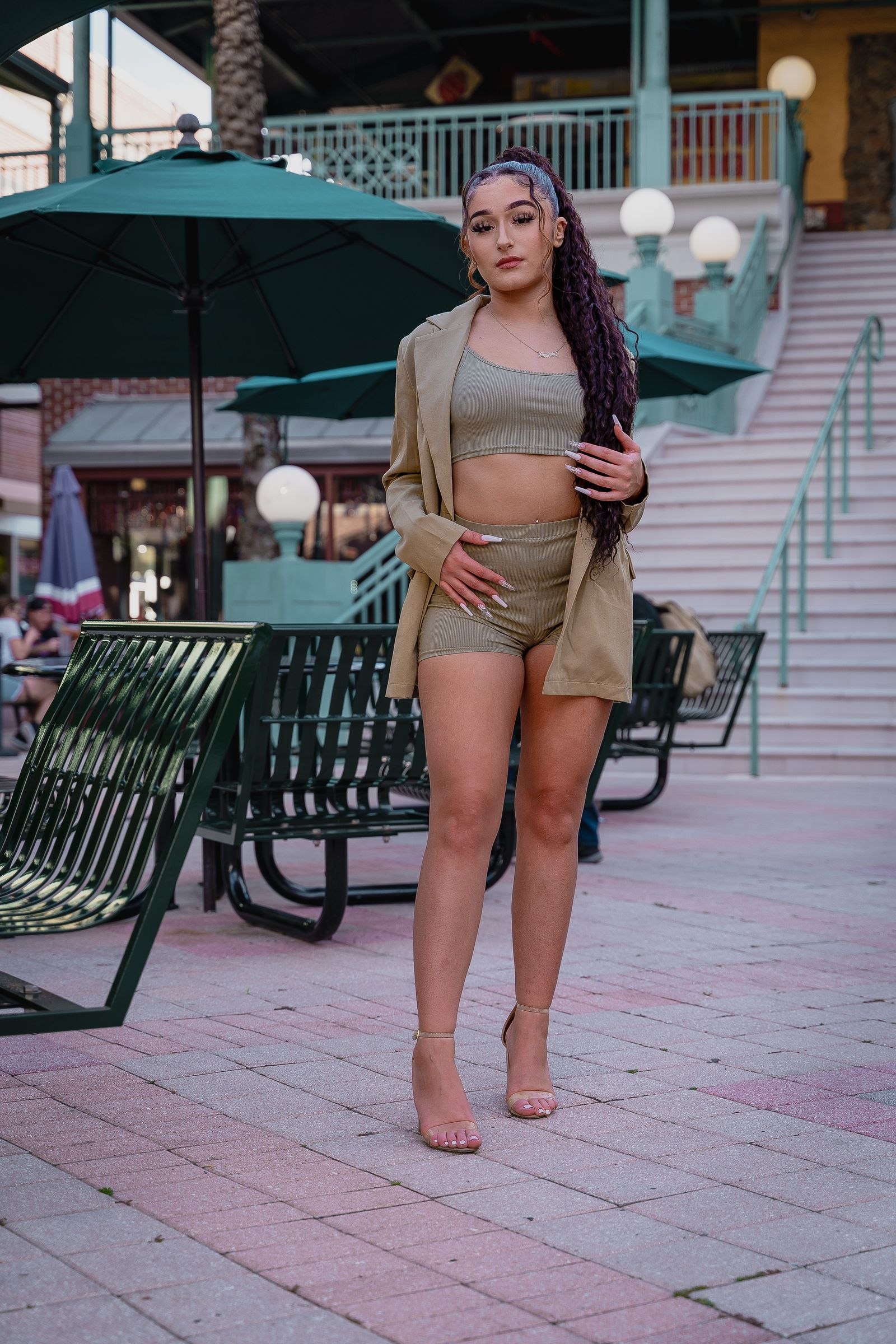 A woman wearing a beige jacket, matching shorts, and a light cropped top.