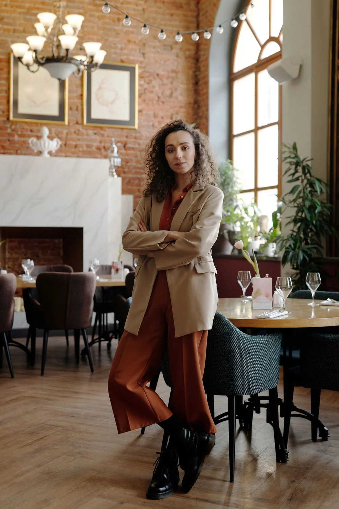 A woman wearing a tan blazer beside a restaurant table.