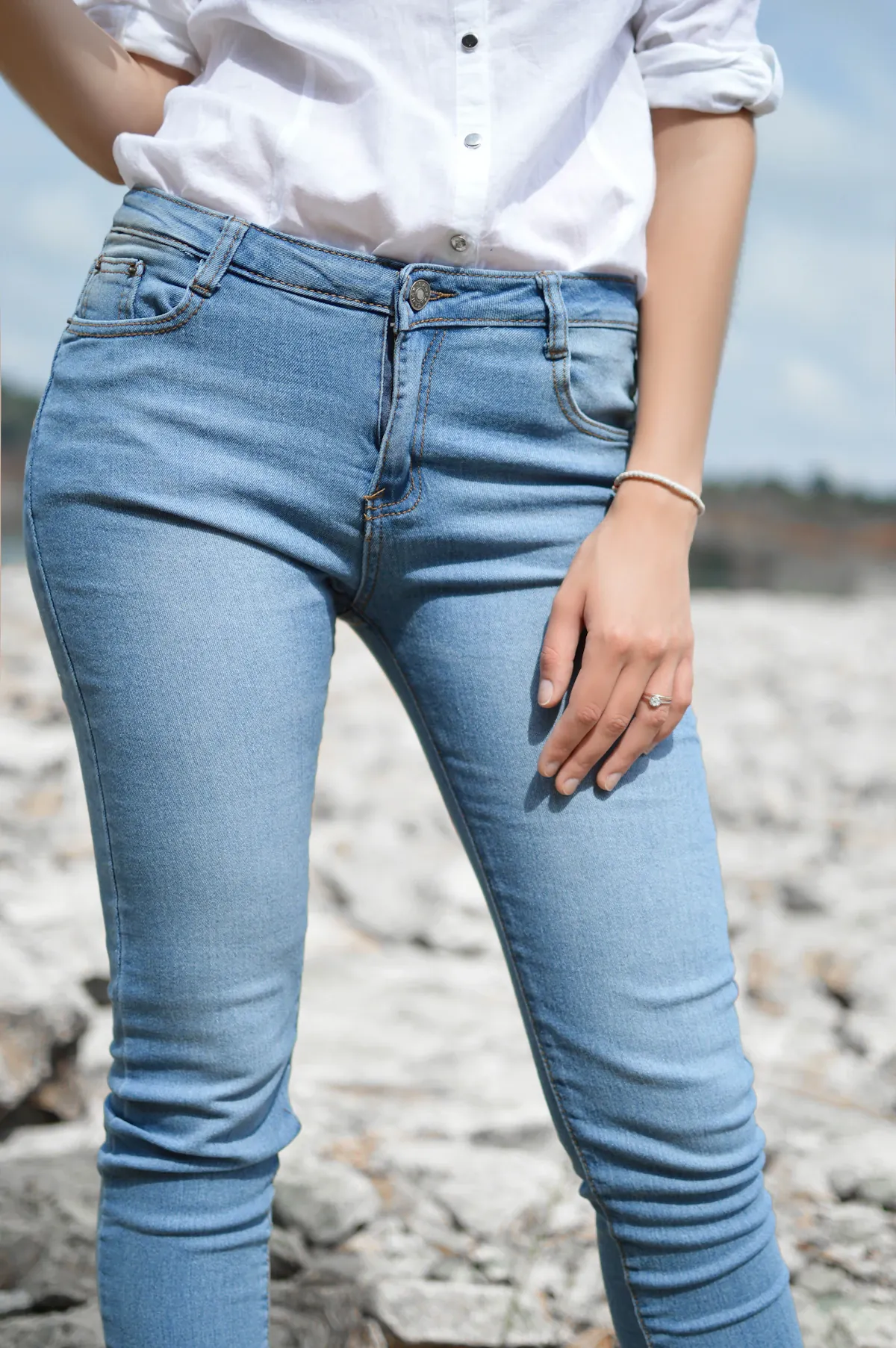 A close view of a white shirt tucked into blue jeans.