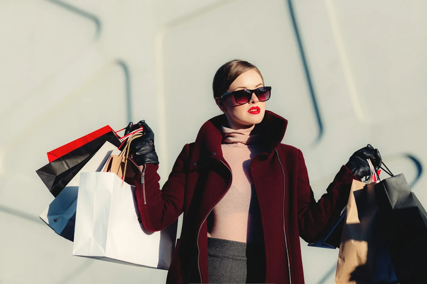 A woman wearing sunglasses and holding several shopping bags.