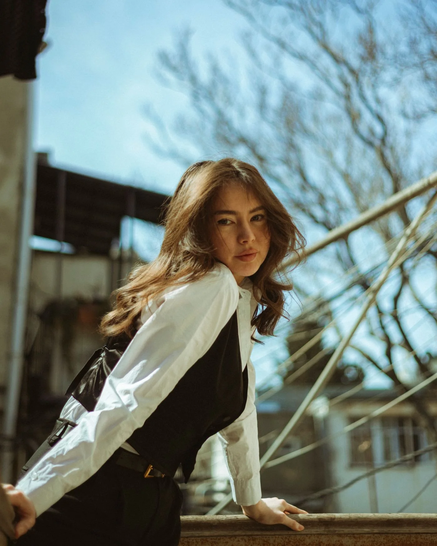 A woman wearing a white blouse and dark waistcoat outdoors.