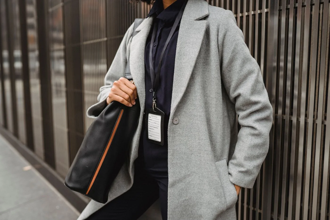 A woman wearing a grey coat with a black shoulder bag.