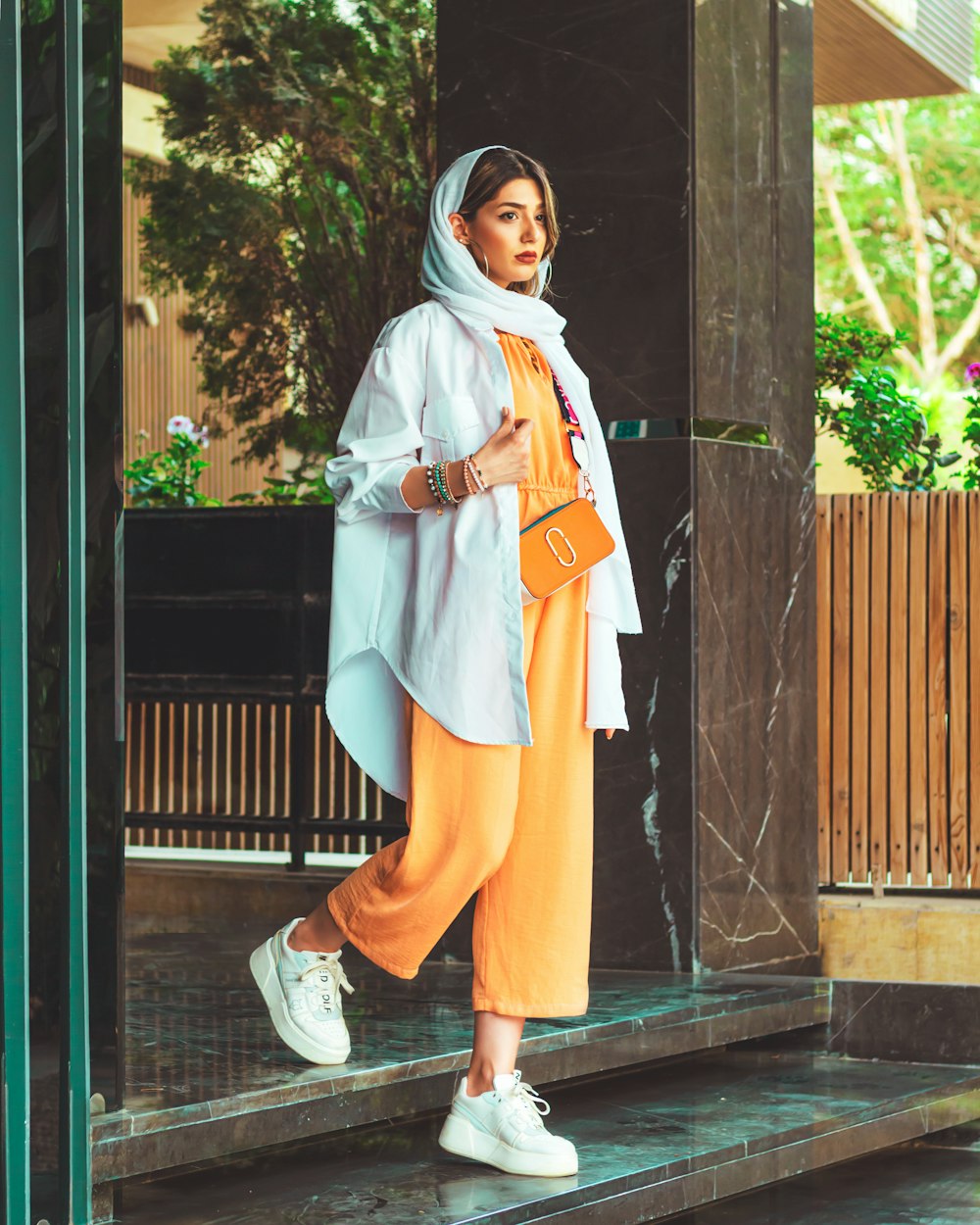 Woman wearing a light blue shirt over an orange outfit outdoors