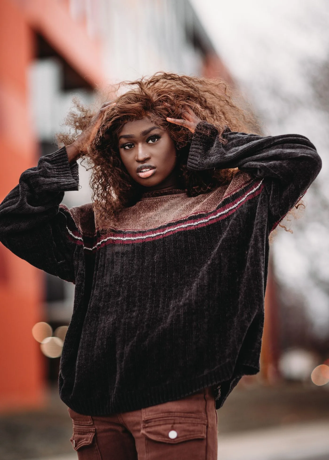 A woman in a dark textured sweater standing outdoors.